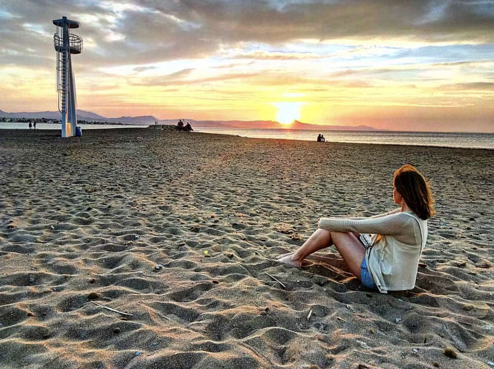 Student sitting on the beach in Denia, Spain