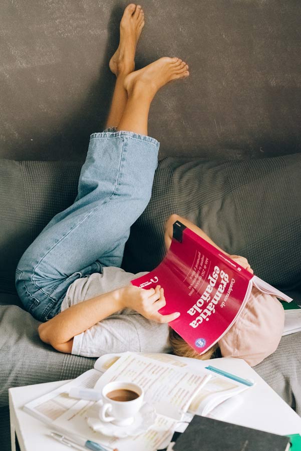 Chica en el sofá estudiando con un libro de gramática española